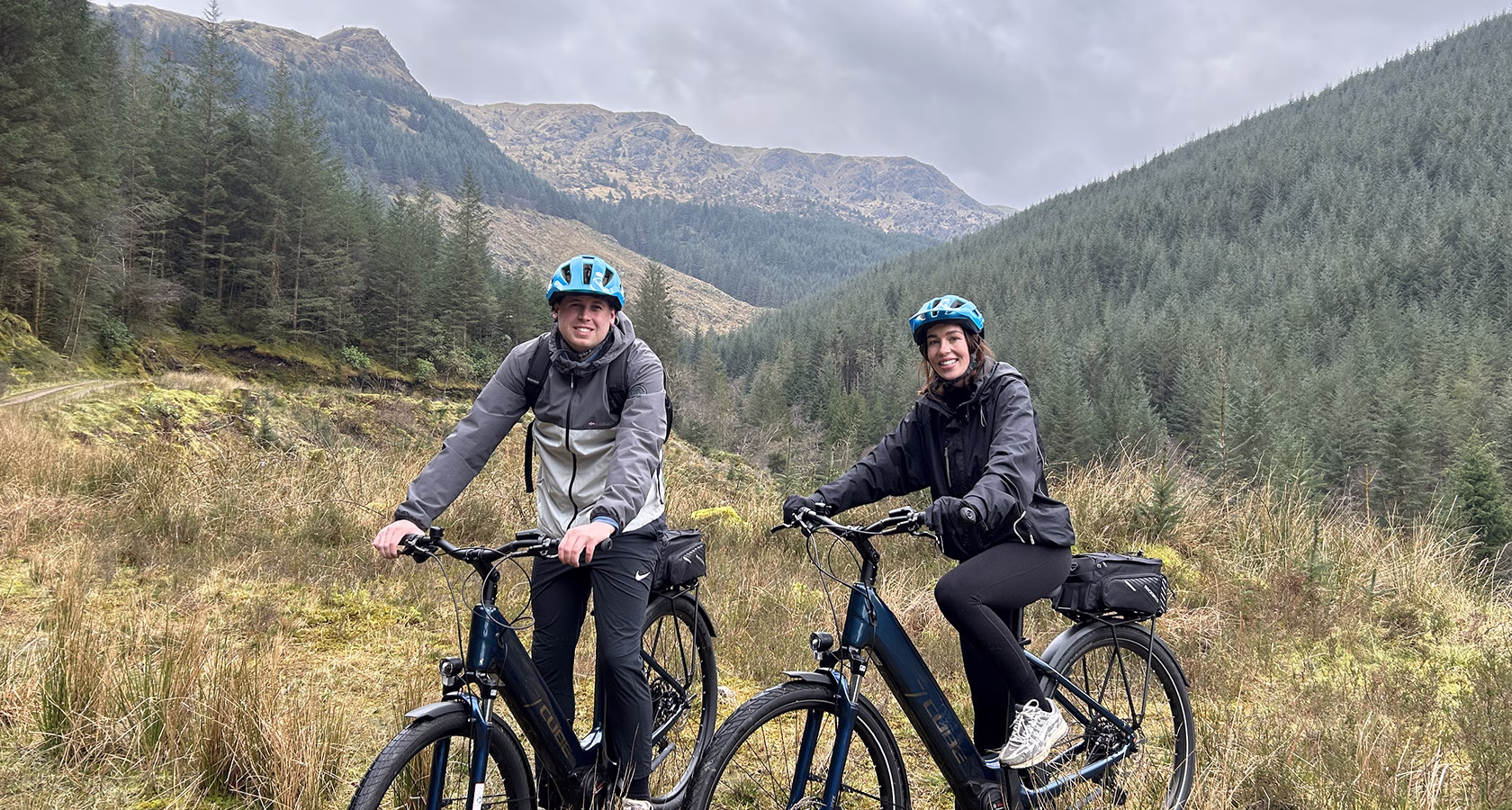 A couple on an e-bike tour in Dunoon with mountains in the background